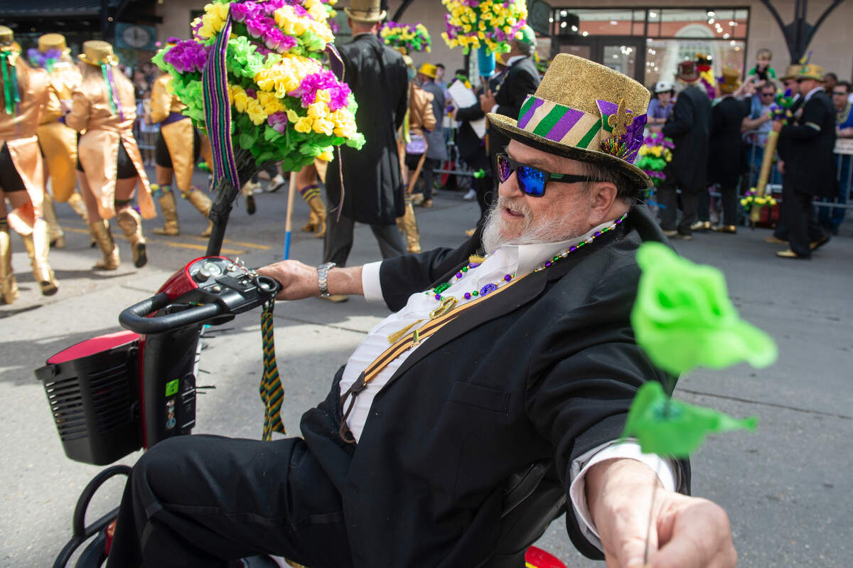 A member of the Ole Biloxi Marching Club passes out flowers during the Ocean Springs Elks Club Mardi Gras Parade in Ocean Springs on Saturday, Feb. 15, 2025.