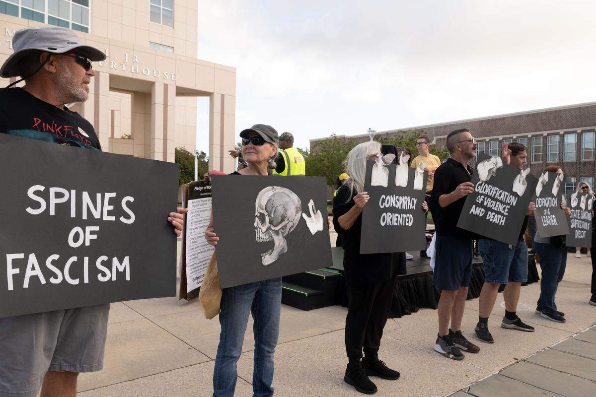 Protesters hold up signs depicting the “Spines of Fascism.”