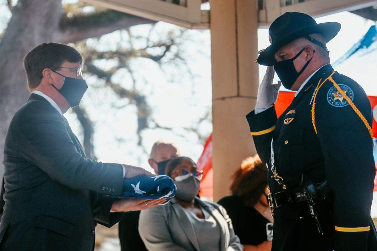 A Hancock County sheriff’s deputy hands a folded American flag to Gov. Tate Reeves, who presented it to the wife of slain deputy Lt. Michael Boutte at the funeral service Tuesday, Feb. 9, 2021.
