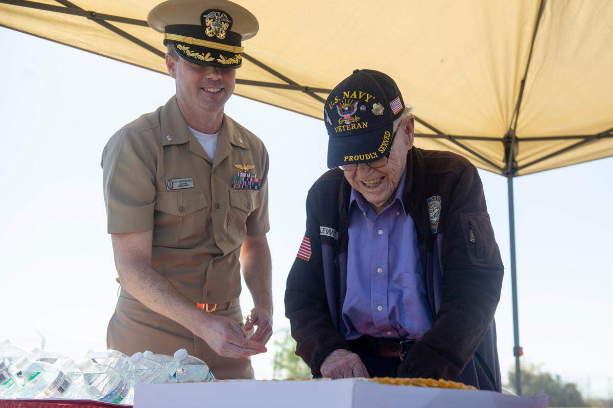 Commander Ryan McGoldrick, left, helps WWII veteran Alfred Lewis cut Lewis’ birthday cake during a ceremony for Lewis at Singing River Island in Pascagoula on Saturday, March 22, 2025.