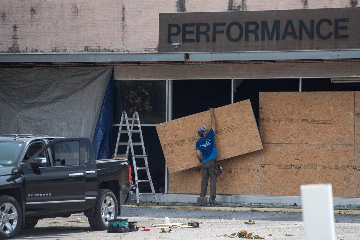 A worker boards up an auto body shop in Moss Point on Tuesday, June 20, 2023, after a tornado tore through the town on Monday.