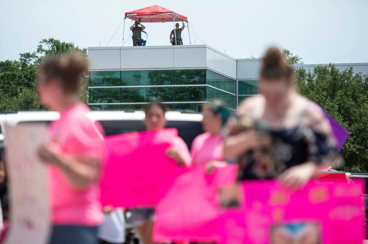 Members of law enforcement watch protestors from the roof of the Jackson County General Services building as a hearing in a chancery court case involving Heather Wyatt takes place in the adjacent courthouse on Thursday, July 18, 2024.