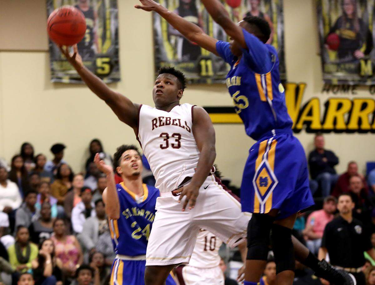 AMANDA McCOY/SUN HERALDGeorge County's D'Wan Williams, center, stretchs for a shot while guarded by St. Martin's Jalen Lett, right, takes a shot while competing against St. Martin on Friday, Feb. 19, 2016, at D'Iberville High. George County defeated St. Martin 64-58 to win the Region 7-6A championship. 