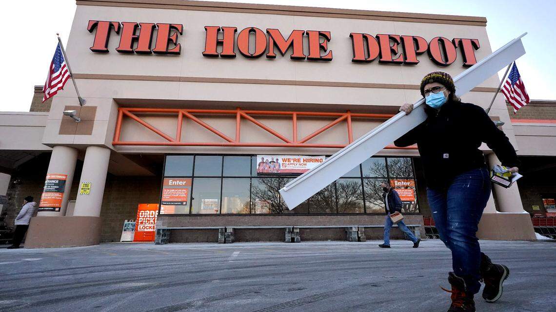 Passersby walk near an entrance to a Home Depot on Feb. 21 in Boston. The home improvement store joins a growing number of retailers requiring both customers and employees to wear a face mask. (Steven Senne/AP)