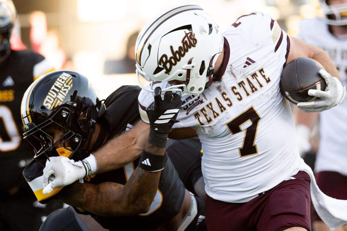 Southern Miss safety Dylan King (6) grabs the facemask of Texas State running back Lincoln Pare (7).