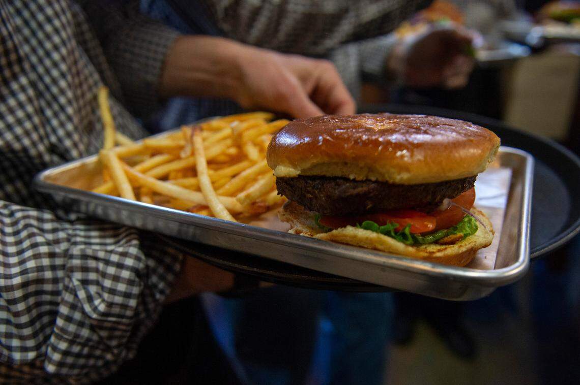 A waiter carries a tray featuring a hamburger being served during a lunch for Biloxi’s first responders at Ground Zero Blues Club in Biloxi on Thursday, Feb. 10, 2022. The menu for the venue will feature some of the most popular dishes from the original Ground Zero Blues Club in Clarksdale and some new offerings with Coast flavor.
