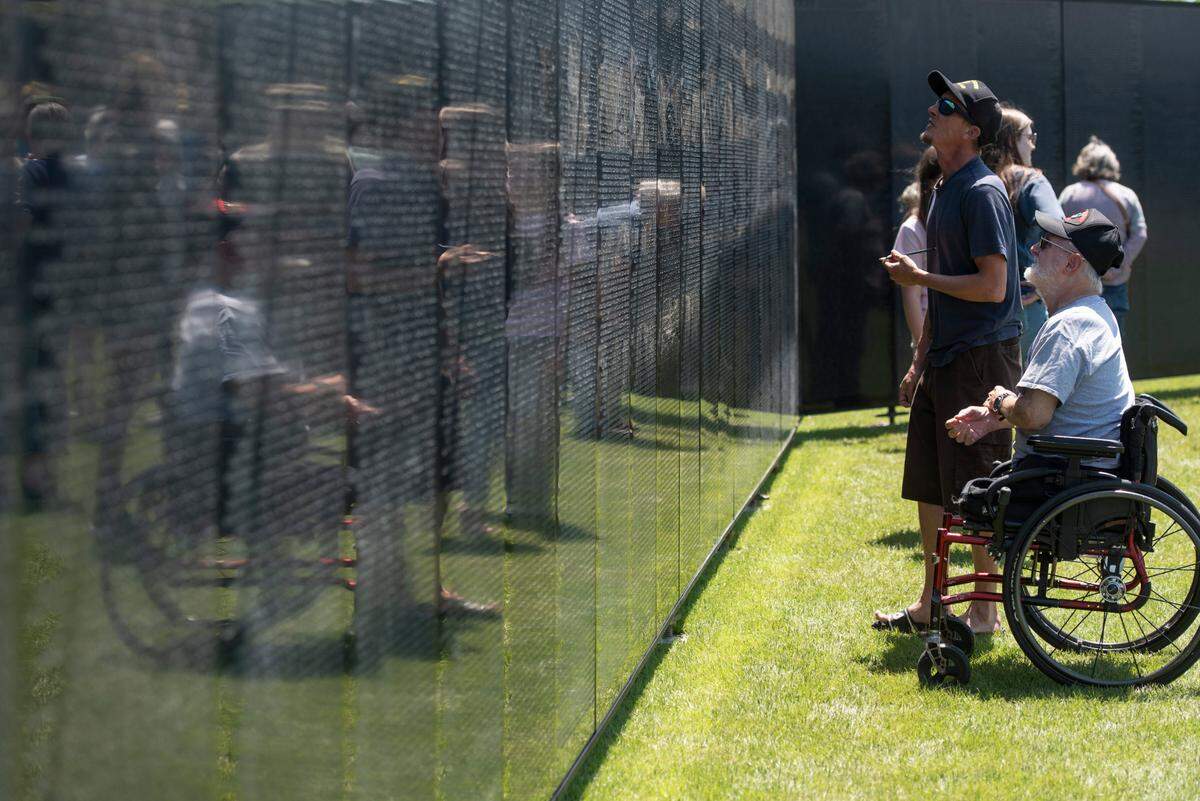 Visitors look at names on The Wall That Heals, a traveling three-quarter scale replica of the Vietnam Veterans Memorial in D.C., while it is on display at the D’Iberville Sports Complex in D’Iberville on Thursday, April 10, 2025.