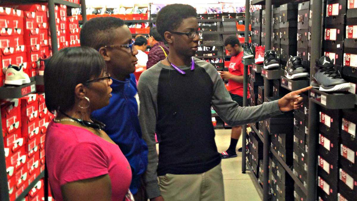 MARY PEREZ/SUN HERALDTyreke Jackson, right, point out the style of shoes that he liked to his twin brother, Tyrell Jackson, and his mother, Latasha Jackson. The family from Florida were shopping at Gulfport Premium Outlets and said the styles the pros wear and friends favor influence their choice of athletic shoes.