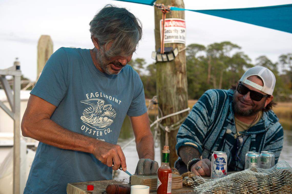 Matthew Mayfield, a co-owner and co-founder of Eagle Point Oyster Co., shucks oysters for a friend at Ocean Springs Harbor on Friday, As natural reefs have become less productive, Eagle Point and other companies are raising oysters in off-bottom cages south of Deer Island in Biloxi.