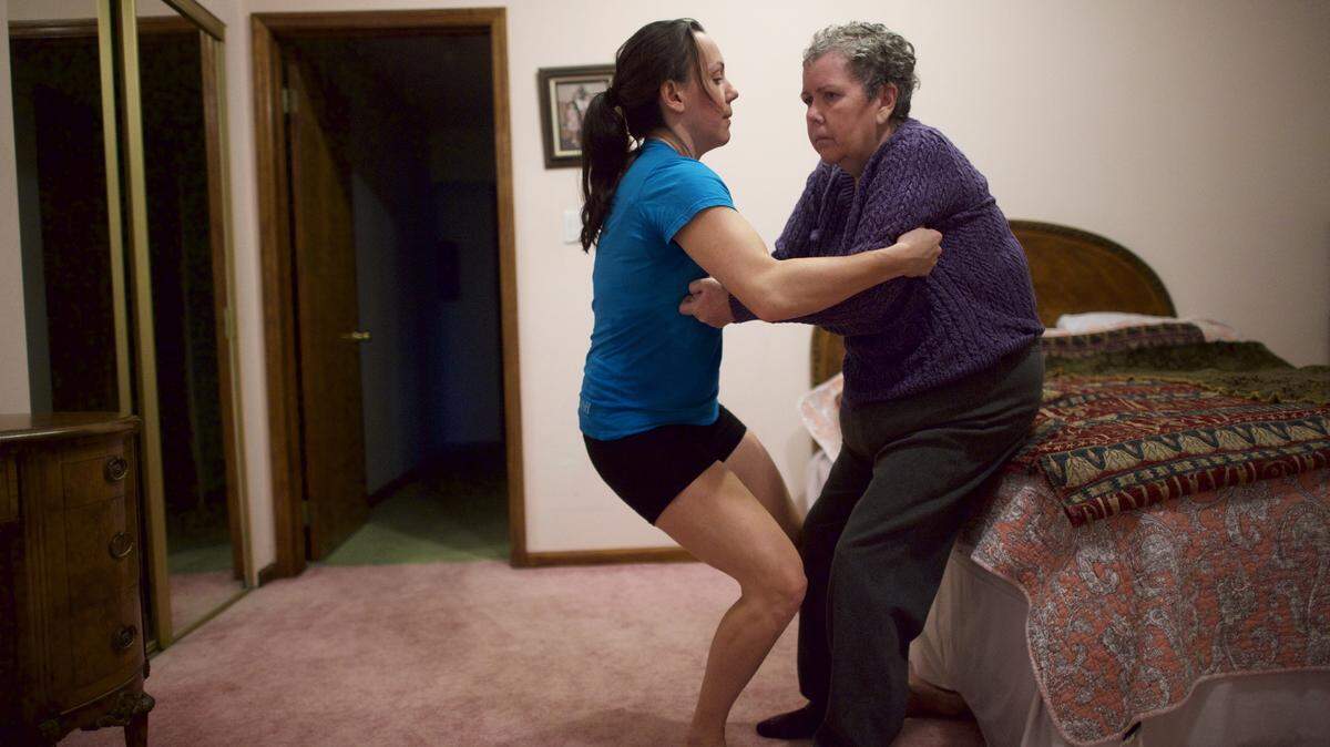 Elizabeth Wolf helps her mother Nancy Brood up to her feet after helping her bathe and dress, at their home in Haddonfield, N.J., Jan 5, 2016. In 2010 Wolf, along with her husband, moved back into her childhood home to help her parents, who both suffer from dementia, expecting to arrange caregiving help and then return home to Vermont: Over five years later, she is still caring for them. (Mark Makela/The New York Times)