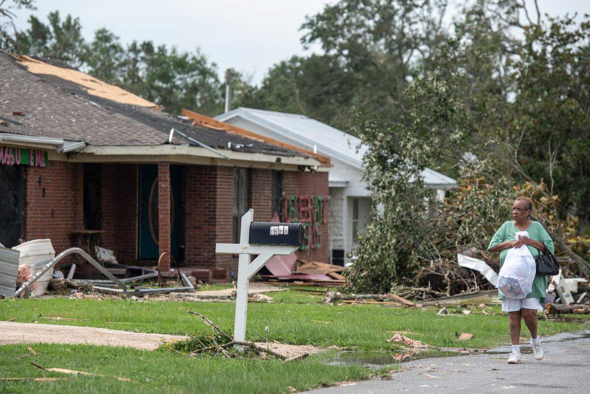 A woman carries personal belongings in a trash bag in Moss Point on Tuesday, June 20, 2023, after a tornado tore through the town on Monday.