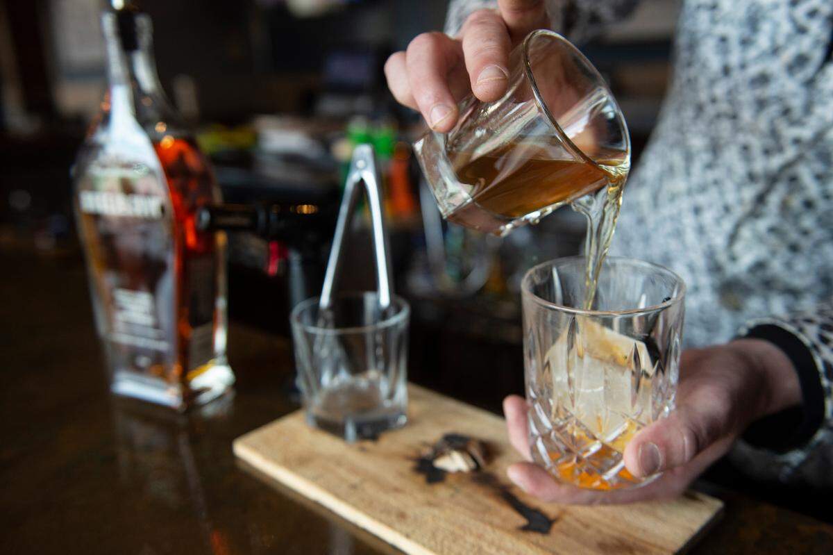 Bartender Jonathan “Jelly” Kelly makes the “Jelly” drink — an old fashioned with Angels Envy bourbon, smoked hickory apricot bitters, honey simple syrup, luxardo cherries and orange peel — at Rackhouse Steaks and Spirits in Gulfport on Tuesday, April 11, 2023.