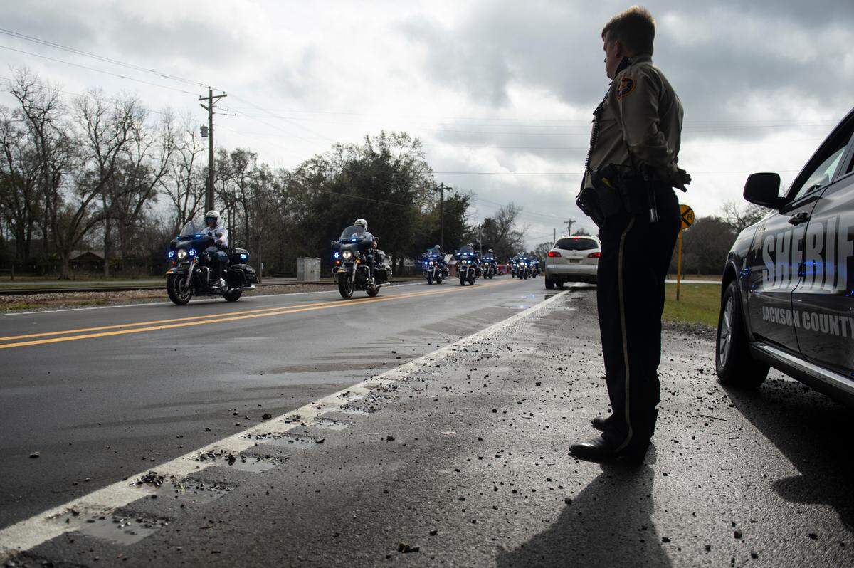 A Jackson County Sheriff’s Deputy stands by as the funeral procession for George County Sheriff’s Deputy Jeremy Malone passes by on Friday, Jan. 12, 2024.