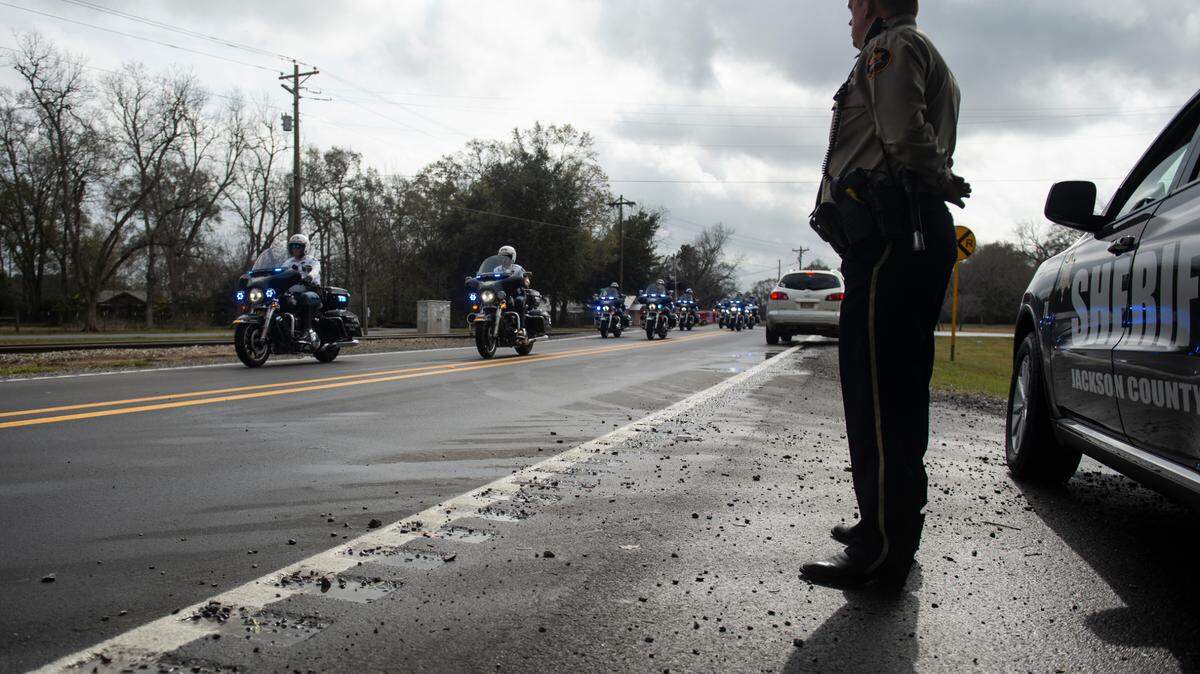 A Jackson County Sheriff’s Deputy stands by as the funeral procession for George County Sheriff’s Deputy Jeremy Malone passes by on Jan. 12.