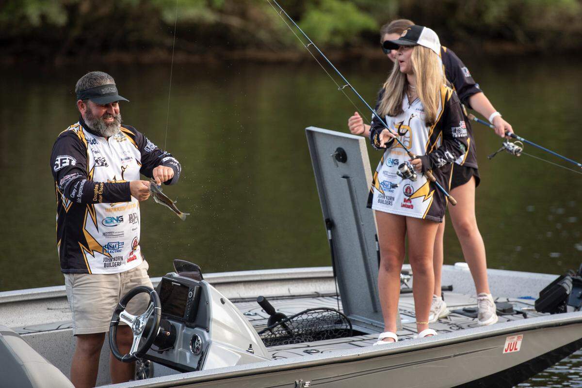 Coach Hiram King helps unhook a fish D’Iberville Bass Fishing Team member Harper Krohn caught while fishing on the Tchoutacabouffa River in D’Iberville with her teammate Olivia King on Monday, June 3, 2024.