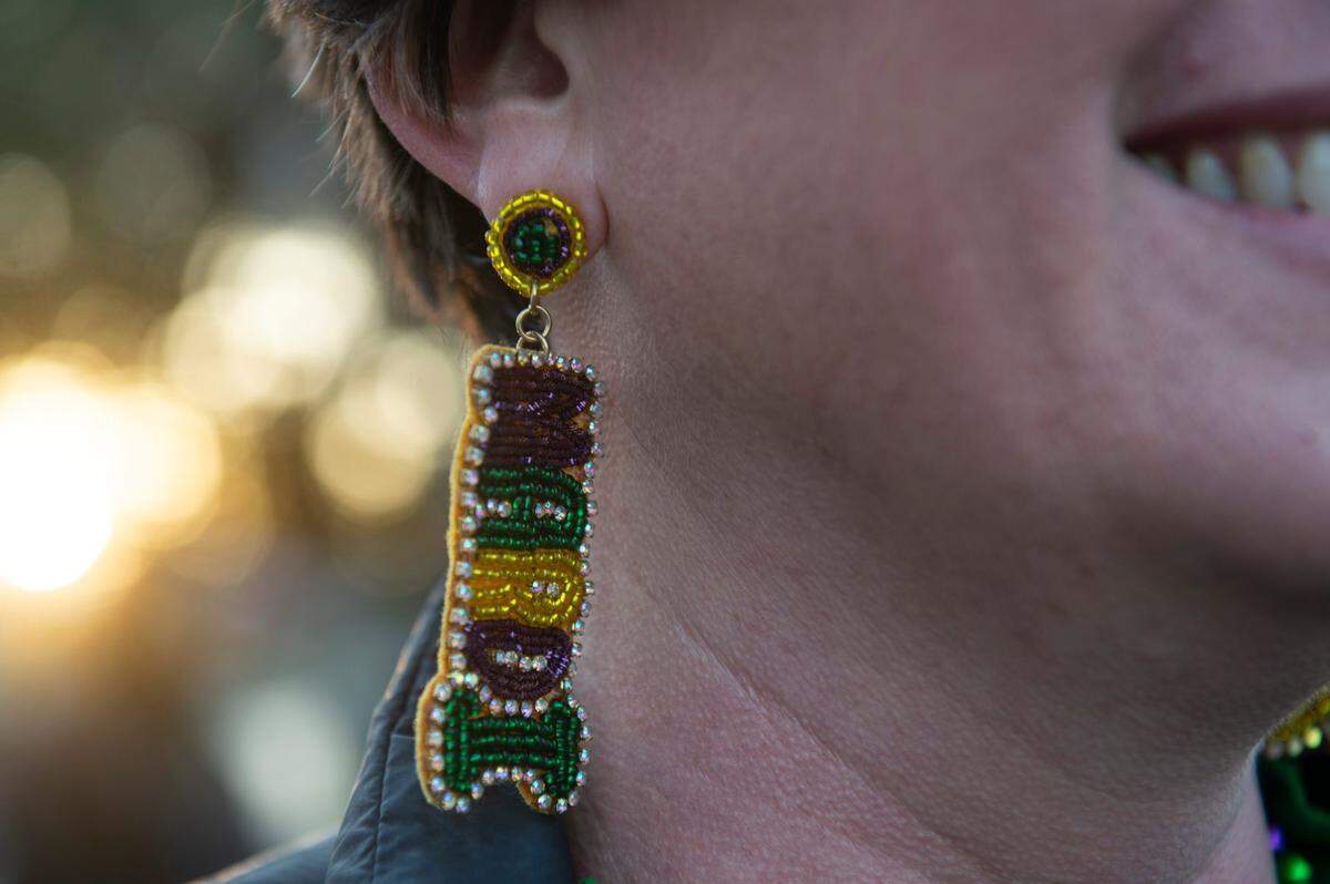 A woman wears Mardi Gras earrings during Mystic Krewe of the Seahorse’s Lundi Gras parade in Bay St. Louis on Monday, March 3, 2025.