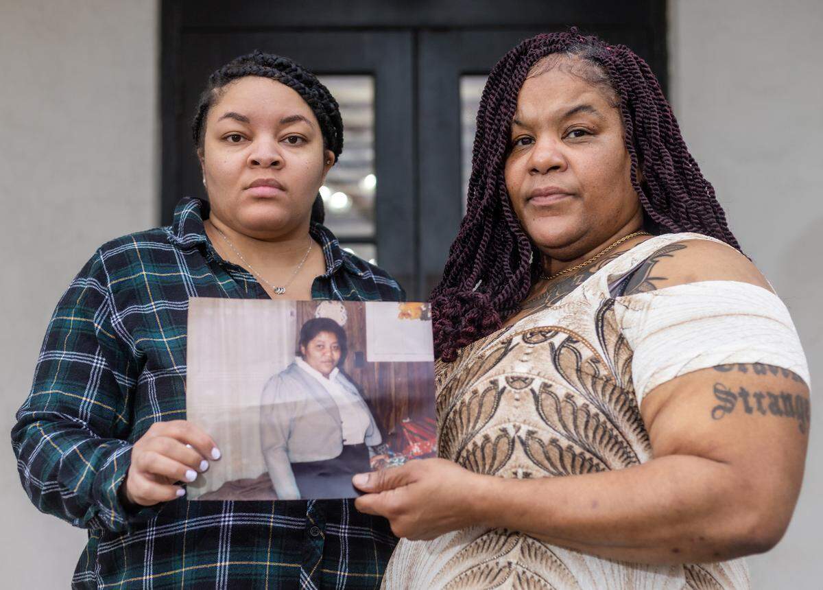 Colett Boston, left, and Everlean Boston hold a photograph of their mother, Mae Evelyn Boston, in Oxford, Mississippi. When the sisters were young, their mother died in jail as she went through the civil commitment process.