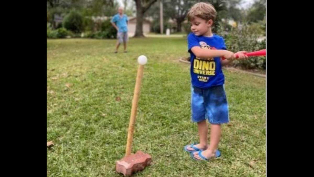 Zachary Dearing practices his swing after his grandfather, Patrick Peterson, fashioned a T-ball stand out of a brick and bamboo.