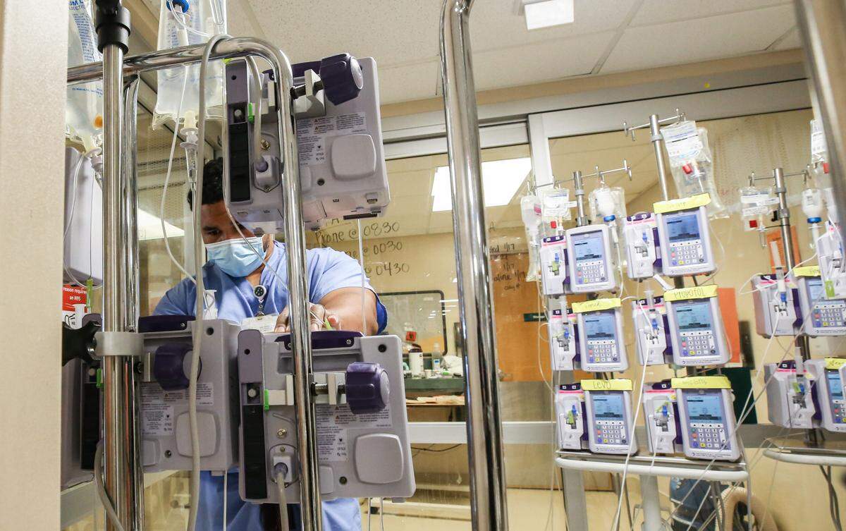 A Memorial Hospital medical staff member monitors a COVID-19 patient’s multiple IVs outside of their room in the intensive care unit Tuesday, January 25, 2021.