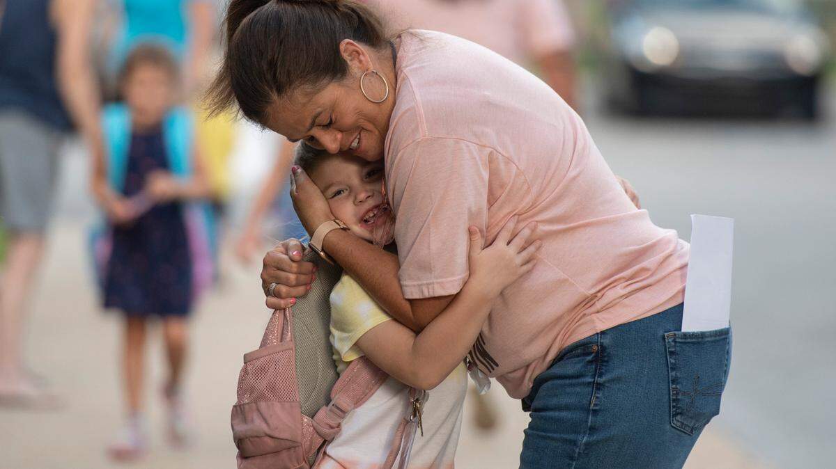 First grader Eliza Greenberg shares a hug with Magnolia Park Elementary school employee Michelle Conley as she arrives back to school on the first day of class at Magnolia Park Elementary on Friday, Aug. 5, 2022.