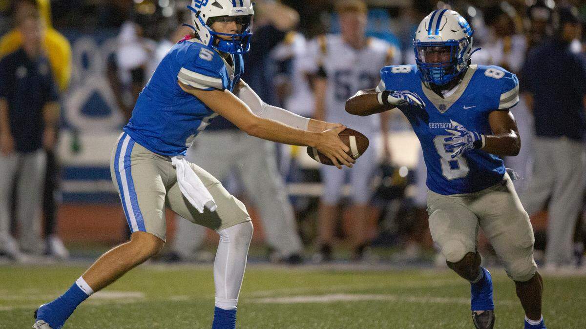 Ocean Springs’ Bray Hubbard, left, sets up a fake pass handoff with Ocean Springs’ Will Smith during a Jamboree game at Greyhound Stadium in Ocean Springs on Friday, Aug. 19, 2022.