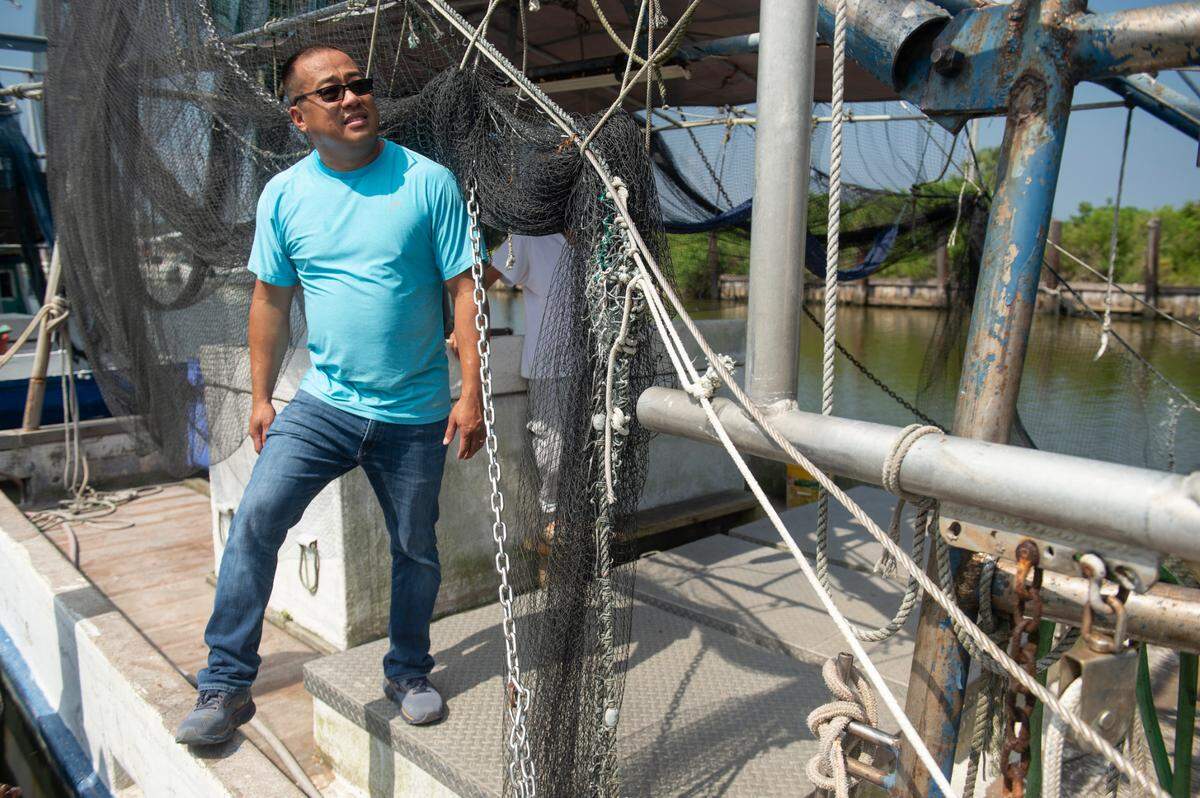 Elvis Ta stands on his father’s shrimping boat, Miss Mimi, at Bayou Caddy in Bay St. Louis on Thursday, June 29, 2023. Instead of following his father into the shrimping industry, Ta works for the Department of Agriculture, owns an HVAC company and DJs for weddings on the side.