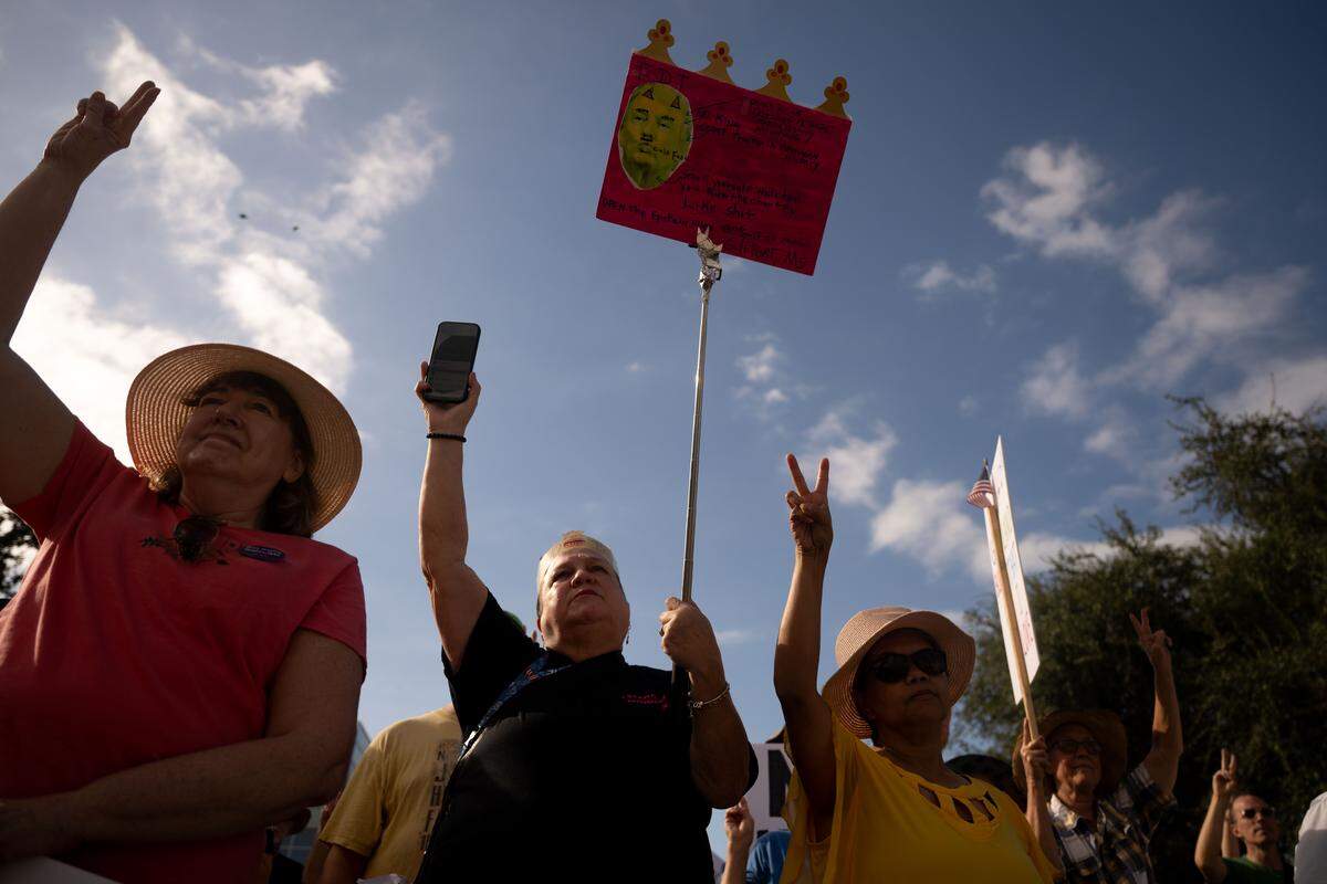Protesters hold up their hands for a vow of peace during the No Kings protest.