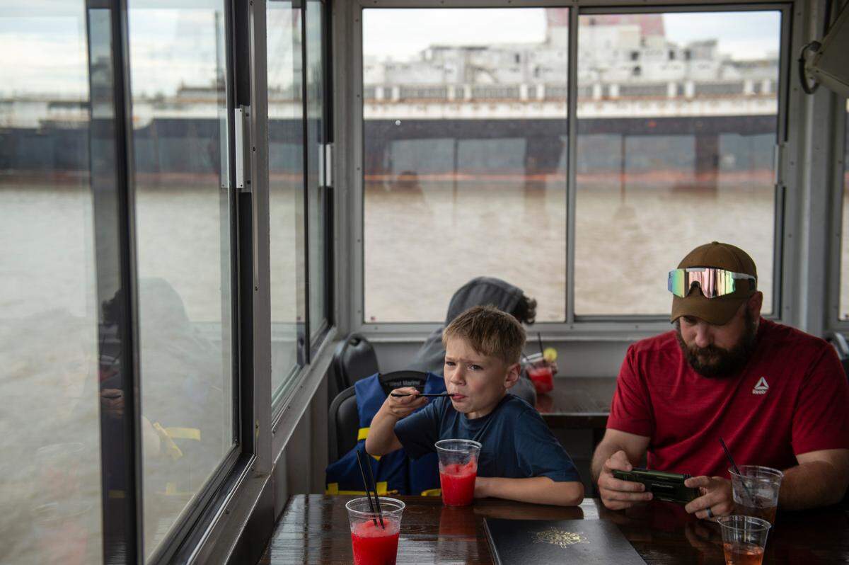 Passengers on The Perdido Queen enjoy drinks as they pass the SS United States in Mobile on Friday, March 28, 2025. The Perdido Queen is offering boat tours of the SS United States while it is docked in Mobile.