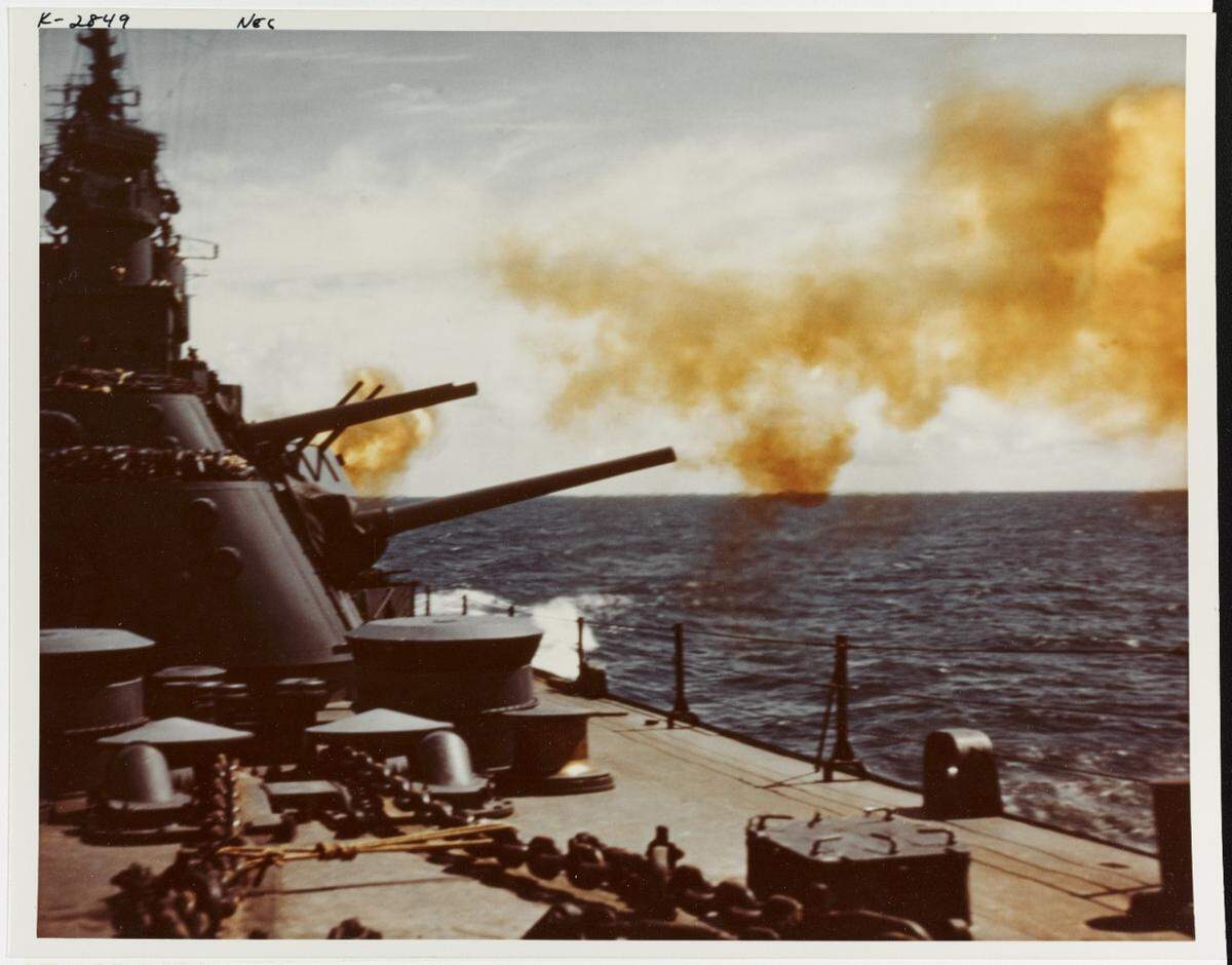 The USS Biloxi firing her 6 inch main battery guns during her shakedown cruise, October 1943. View looking after on the port side.
