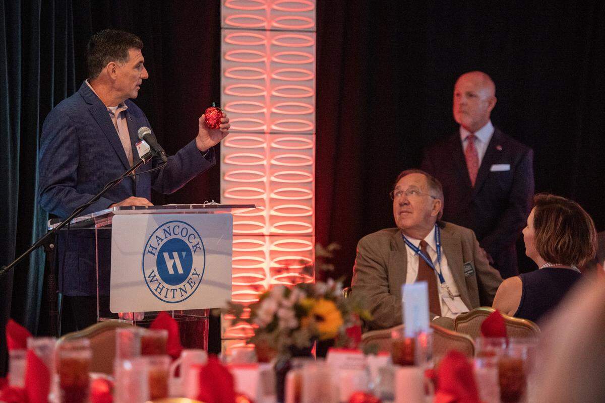 Hancock Whitney Chief Operating Officer D. Shane Loper holds up a chocolate apple given to attendees during the Leo W. Seal awards luncheon at the Great Southern Club in Gulfport on Friday, Aug. 26, 2022.
