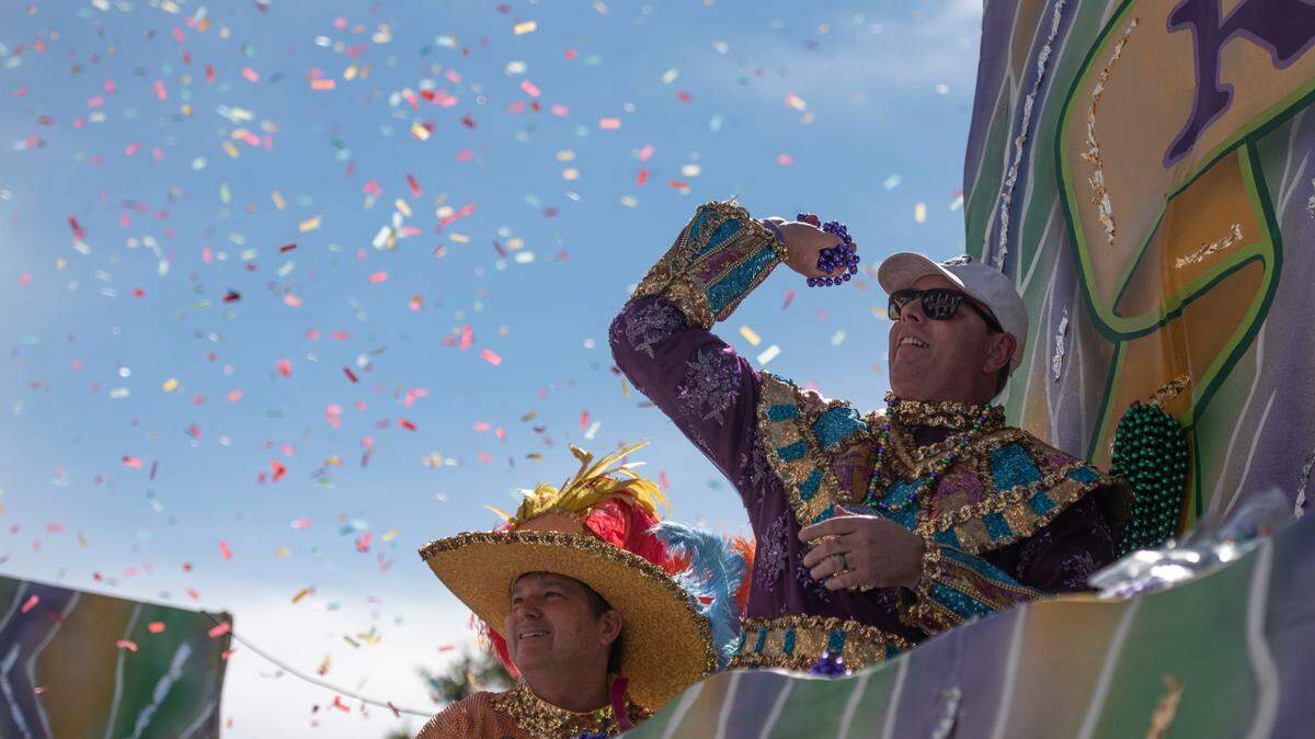 Members of Gulf Coast Carnival Association (GCCA) royalty throw beads to the crowd in front of city hall during the GCCA Mardi Gras parade in Biloxi on Tuesday, Feb. 13, 2024.