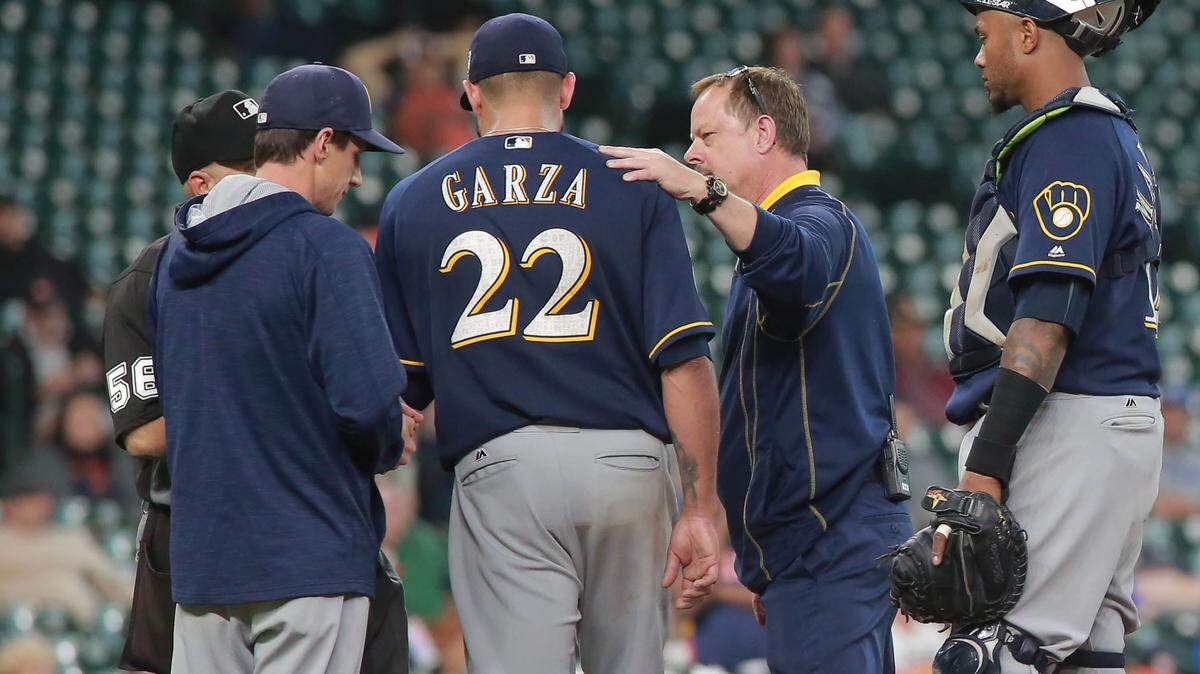 RICHARD CARSON/ASSOCIATED PRESS 
 Milwaukee Brewers pitcher Matt Garza is looked at by a trainer before being taken out in the fourth inning of a exhibition baseball game against the Houston Astros, Friday.