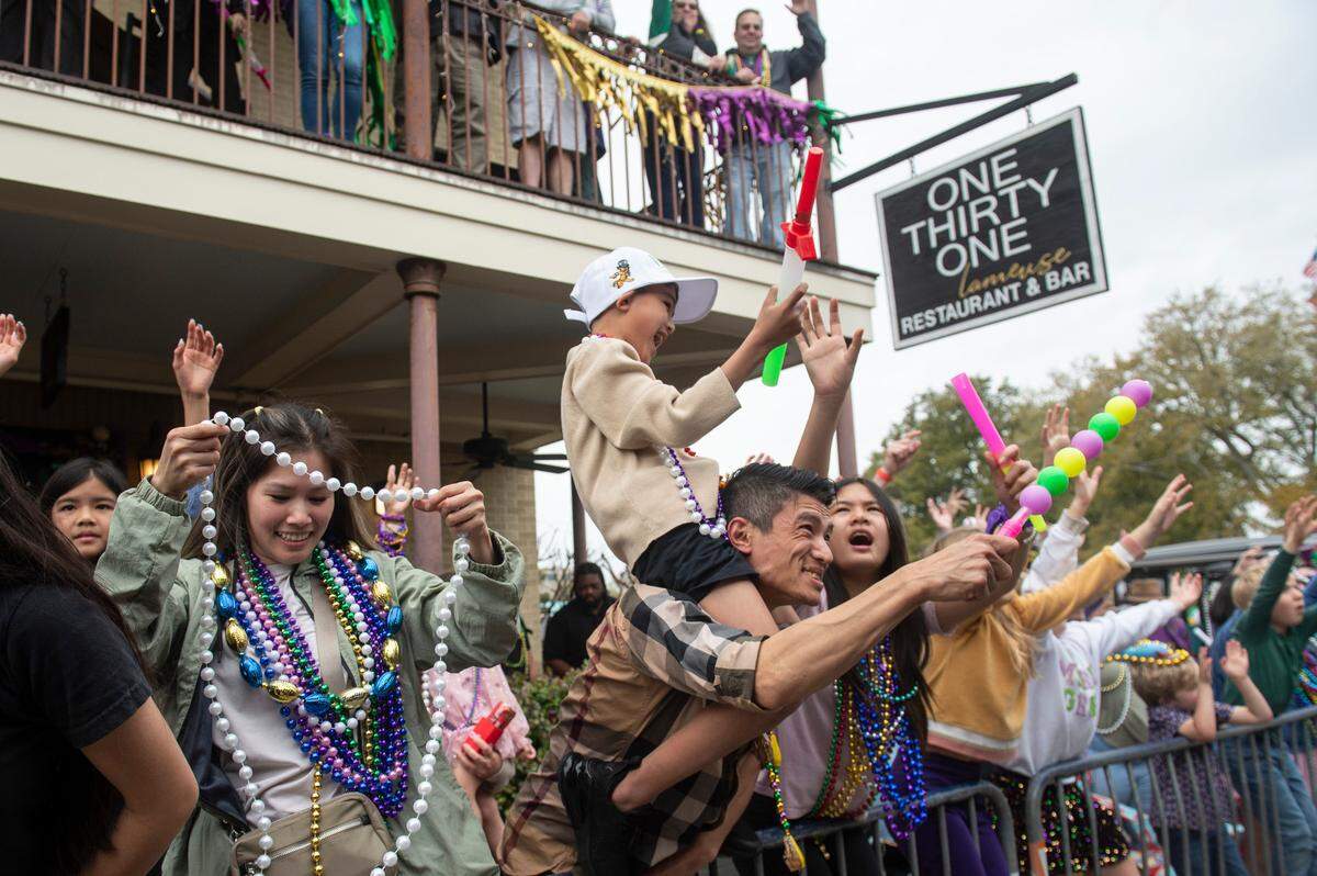 Parade watchers cheer for beads and other throws during the Gulf Coast Carnival Association Mardi Gras parade in Biloxi on Tuesday, March 4, 2025.