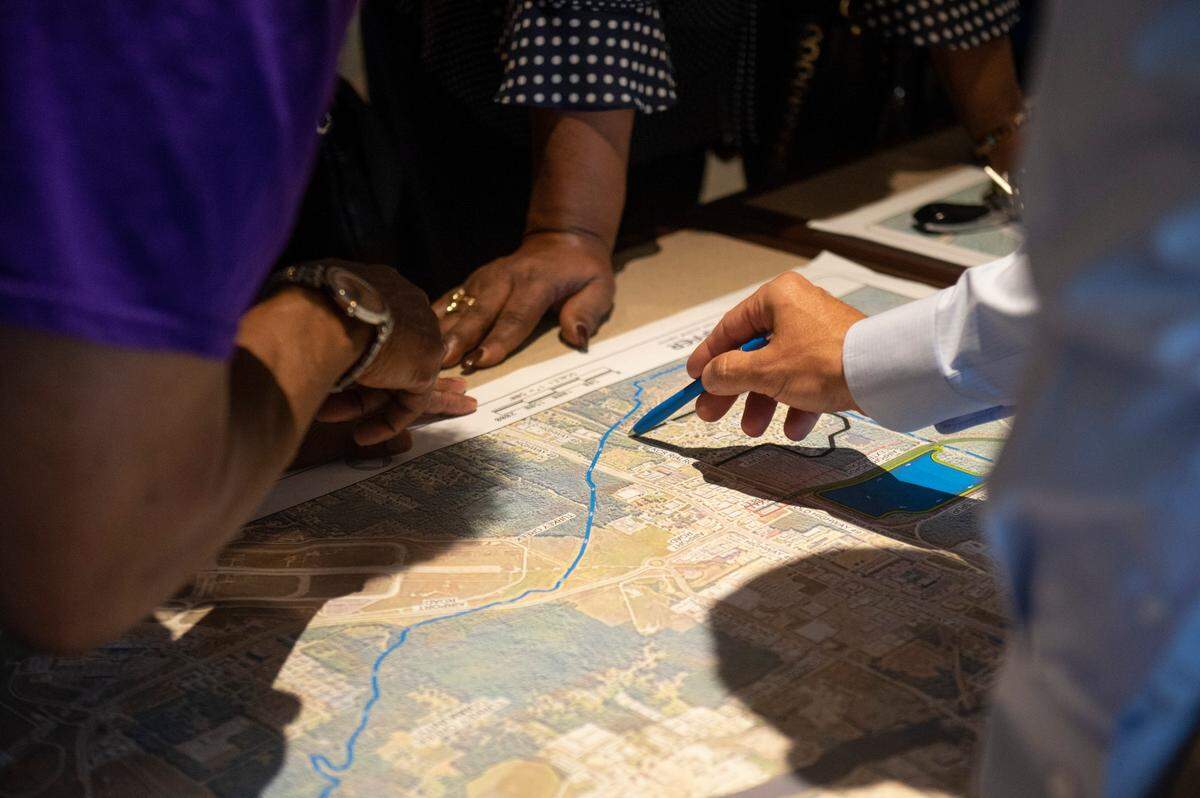 Members of the public go over a proposed road project west of Highway 49 with a representative of Neel Schaffer, the contracting company developing the project, during a public hearing on the road project at Gulfport Premium Outlets in Gulfport on Wednesday, July 13, 2022.