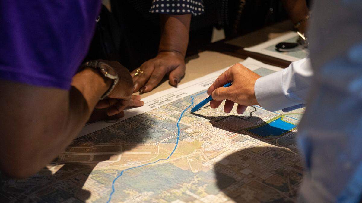 Members of the public go over a proposed road project west of Highway 49 with a representative of Neel Schaffer, the contracting company developing the project, during a public hearing on the road project at Gulfport Premium Outlets in Gulfport on Wednesday, July 13, 2022.