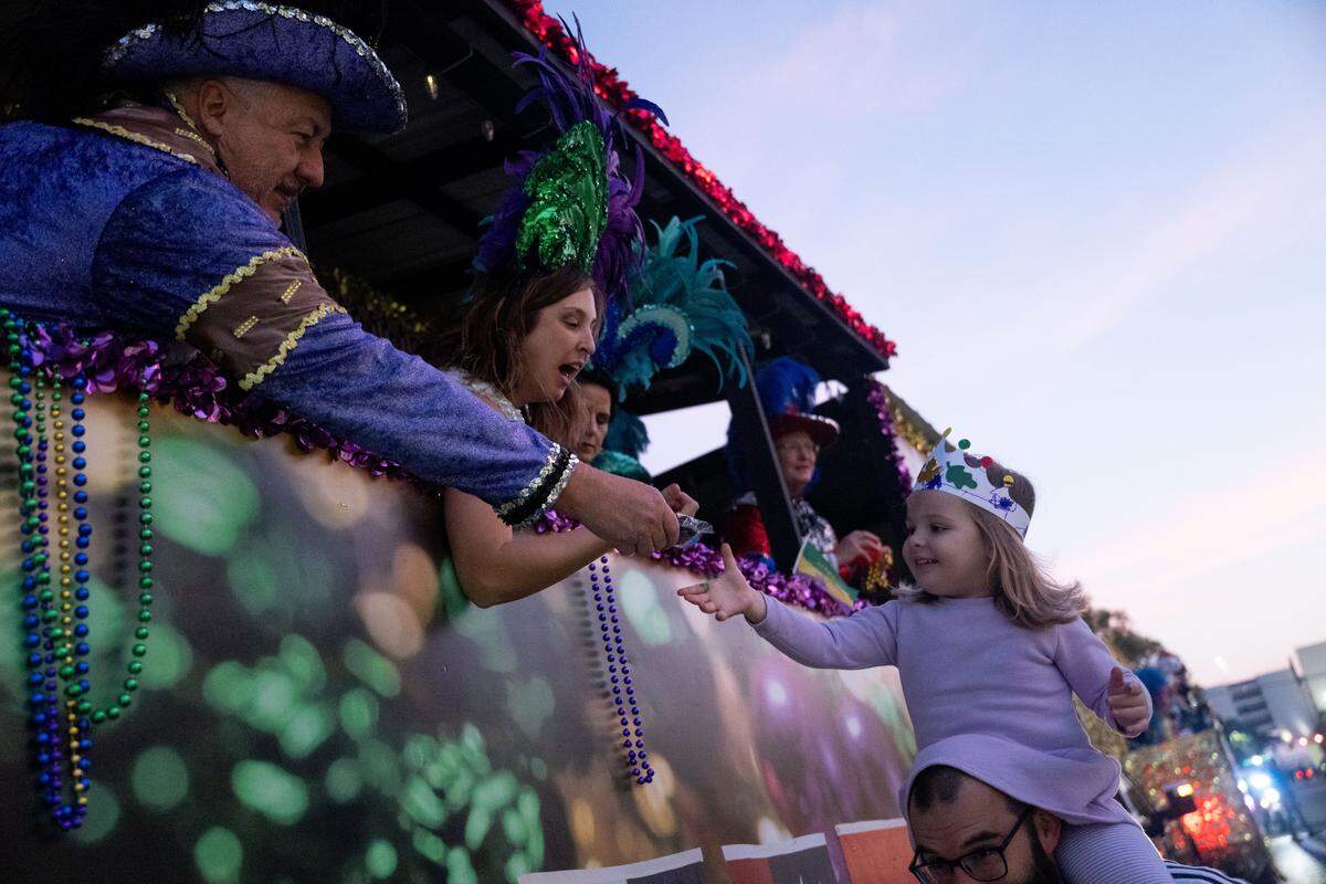 Candy is handed out to a child riding on her father’s shoulders during a 12th Night Celebration in Biloxi on Monday, Jan. 5, 2026.