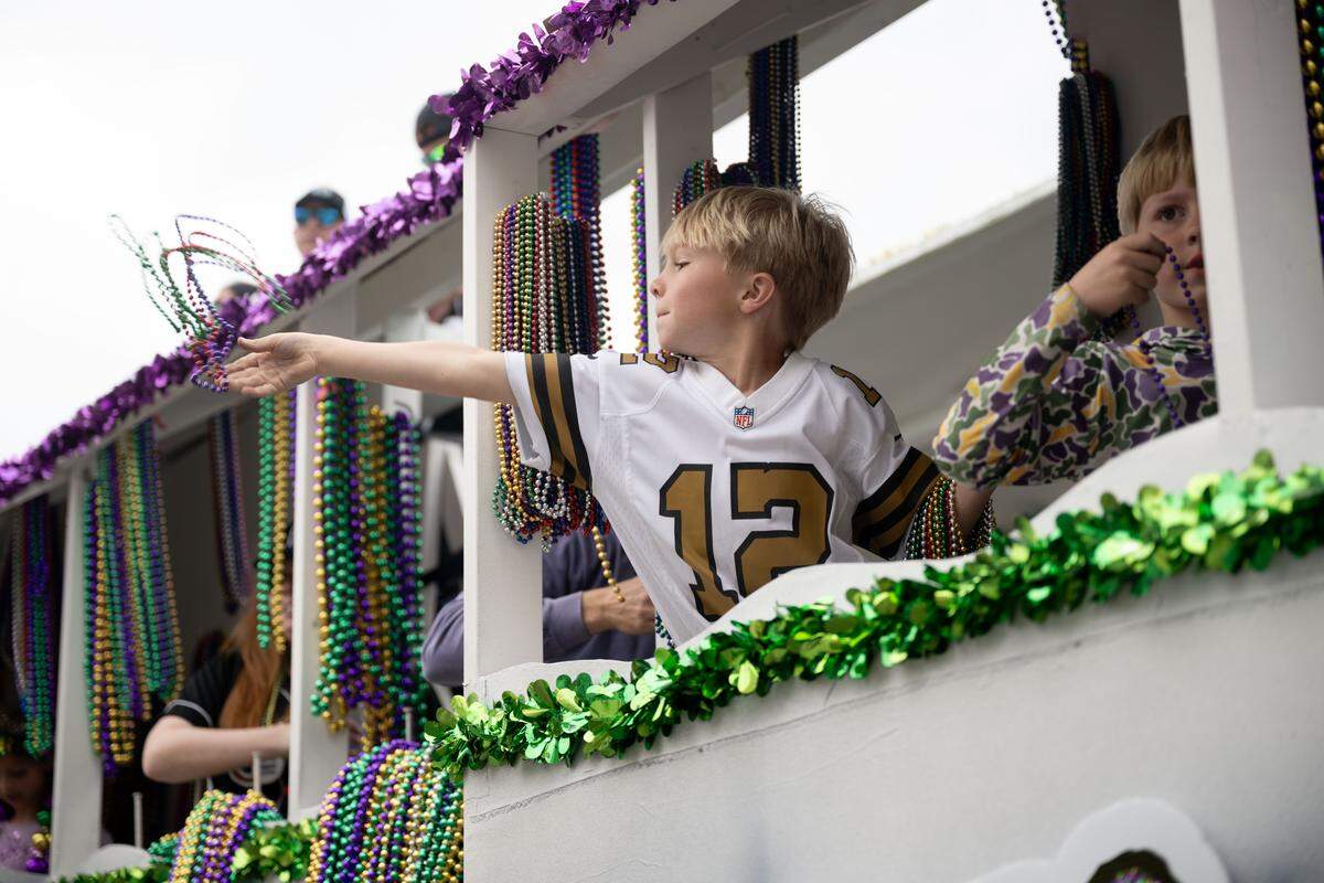 A child throws Mardi Gras beads from a float.