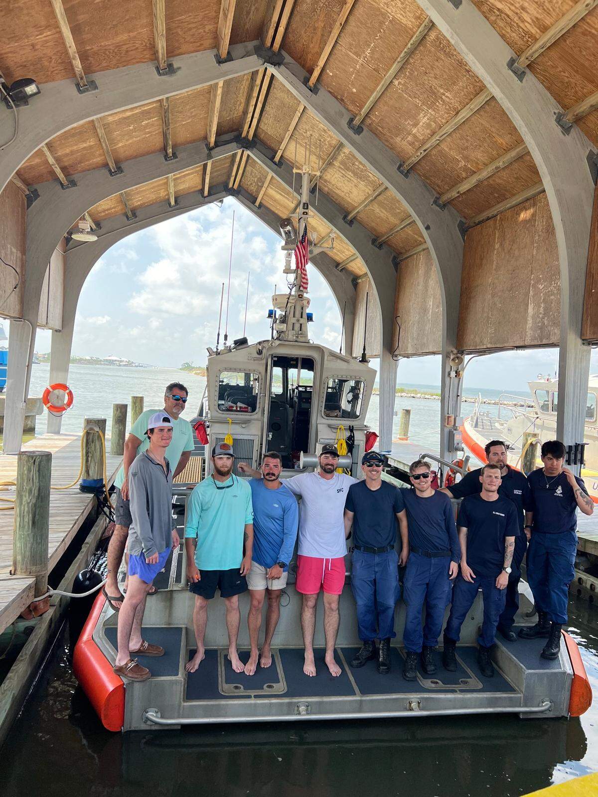 The United States Coast Guard rescued Easton Barrett, pictured fifth from left, and four friends on Saturday after their boat sank and currents carried them to waters off of Dauphin Island, Alabama.