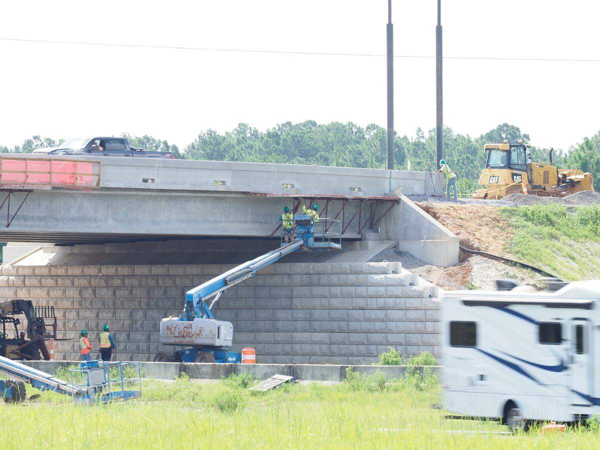 While ground crew members looks on from below and a monitor watches from above, T. L. Wallace employees dismantle the catwalk used to support workers installing the side walls of the new Menge Avenue overpass near Buc-ee’s.