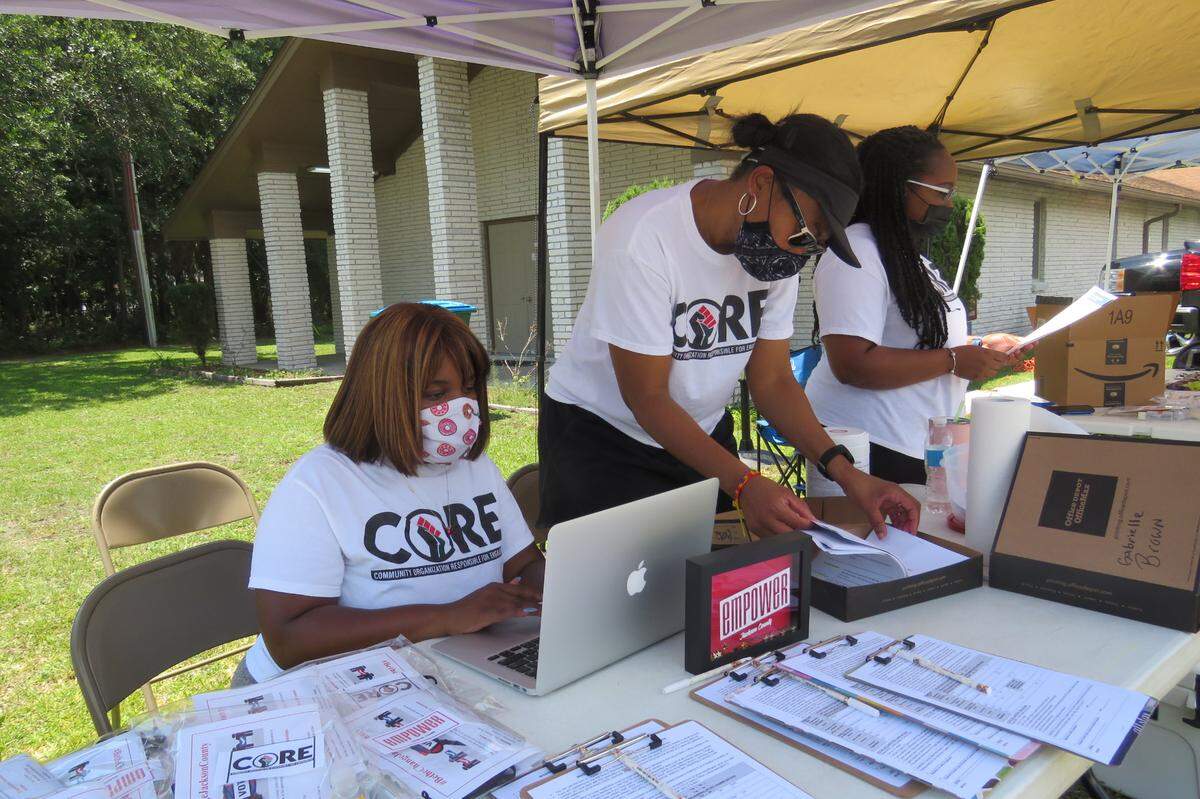CORE members, including Queen Brown, left, organize voter registration forms at the drive-thru registration they held with Empower Jackson County in Gautier on Saturday, Aug. 8, 2020.