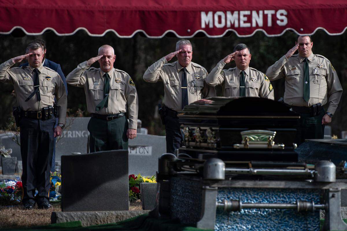 Members of the Jackson County Sheriff’s Department and George County Sheriff’s Department salute the casket during a graveside service for George County Sheriff’s Deputy Jeremy Malone at Tanners Cemetery in George County on Friday, Jan. 12, 2024.
