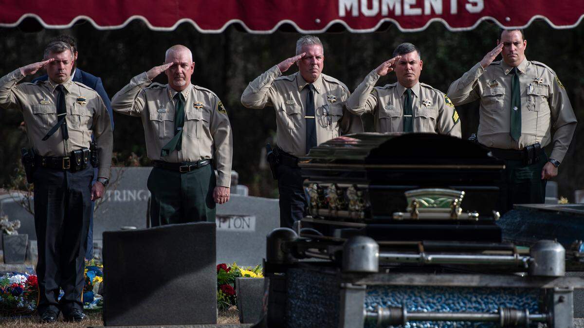 Members of the Jackson County Sheriff’s Department and George County Sheriff’s Department salute the casket Friday during a graveside service for George County Sheriff’s Deputy Jeremy Malone at Tanners Cemetery in George County.