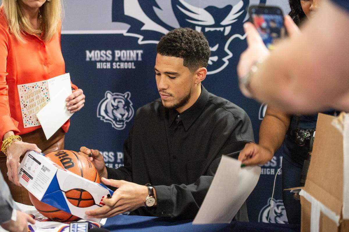NBA star Devin Booker signs autographs before a ceremony for the retirement of Booker’s high school jersey at Moss Point High School in Moss Point on Saturday, Dec. 10, 2022.