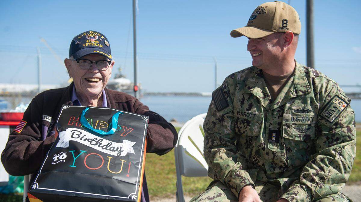 Alfred Lewis, a WWII veteran who fought in the battle of Iwo Jima, opens a birthday gift from the crew of the USS Bougainville during a ceremony for Lewis at Singing River Island in Pascagoula on Saturday, March 22, 2025.
