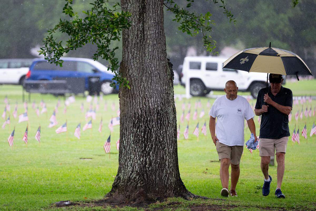 Two event attendees walk through the rain during a ceremony at Biloxi National Cemetery on Monday, May 25, 2026.