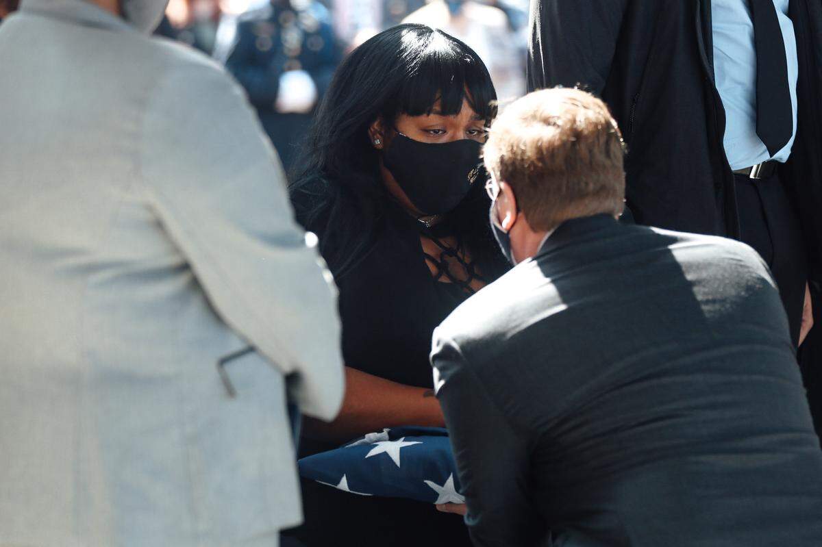 Gov. Tate Reeves hands a folded American flag to Jennifer Mann-Boutte, wife of Lt. Michael Boutte, on Tuesday, Feb. 9, 2021.