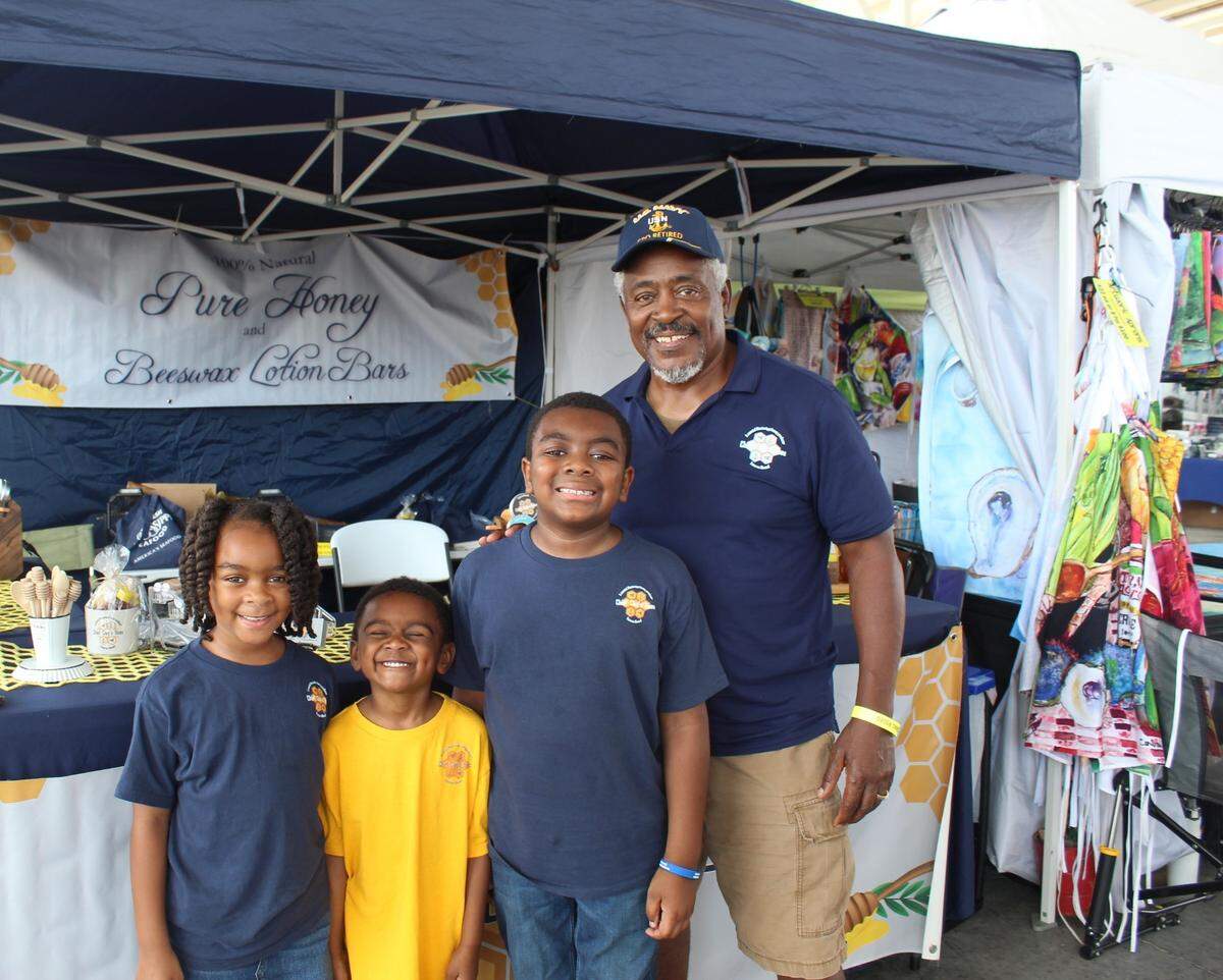 Clabert Guillory poses next to his grandchildren in front of his Chief Clay’s Bees vendor tent at the Deep Sea Fishing Rodeo.