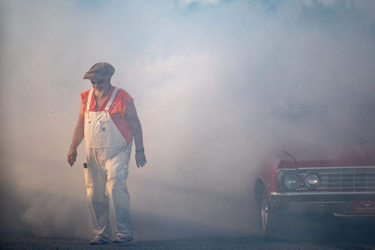 An announcer walks off the burnout track as a car kicks up smoke during Burn ‘Em Up In The Pass on Thursday, Oct. 9, 2025.