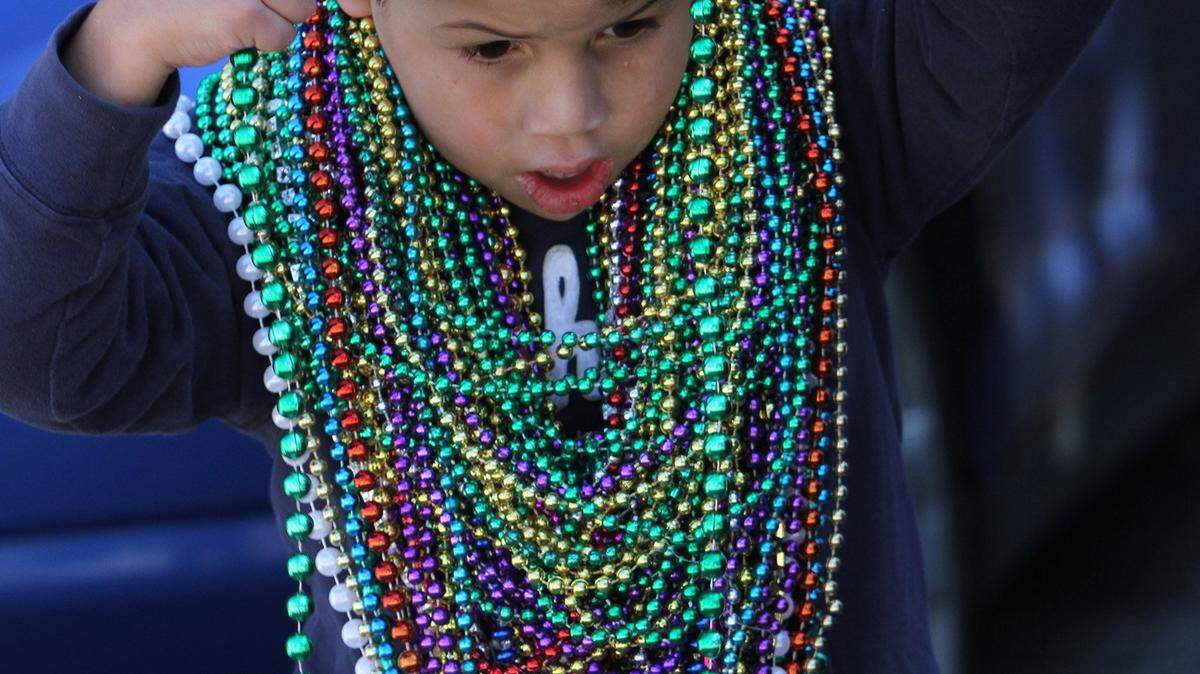 JOHN FITZHUGH/SUN HERALD 
 Jaeden Evans, 5, of Moss Point adds another strand of beads to his collection during the Ocean Springs Elks Lodge Mardi Gras parade on Saturday Jan. 23, 2016.