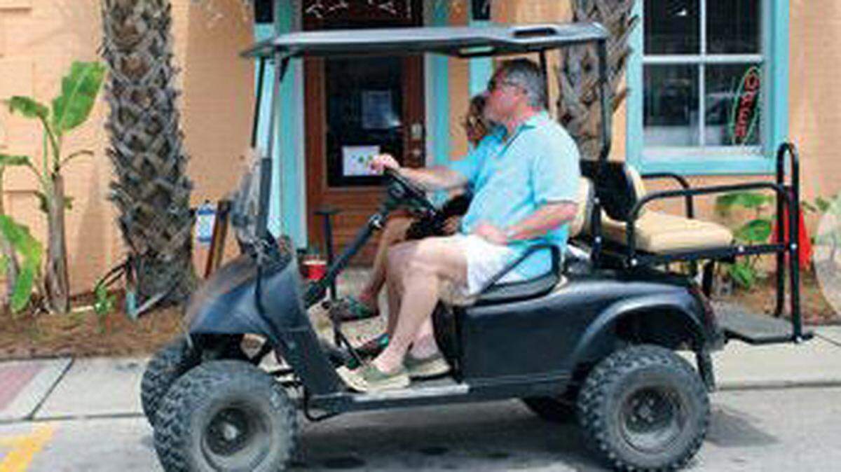 A couple and their dog prepare to take a drive down Court Street in Bay St. Louis. Beginning May 31, carts will be legal in Ocean Springs.
